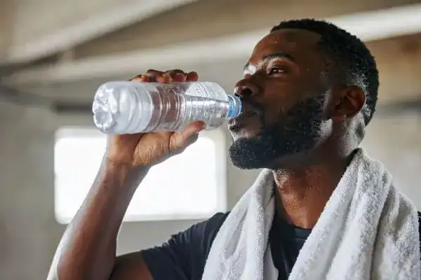 Image of man drinking water to improve hydration Swindon after work out.